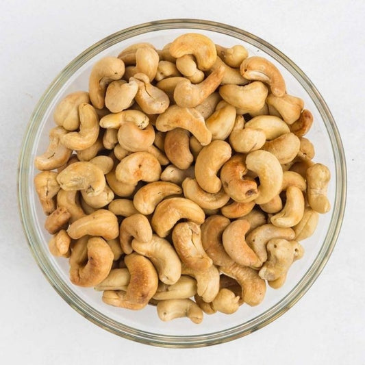 Glass bowl filled with cashews on a white background