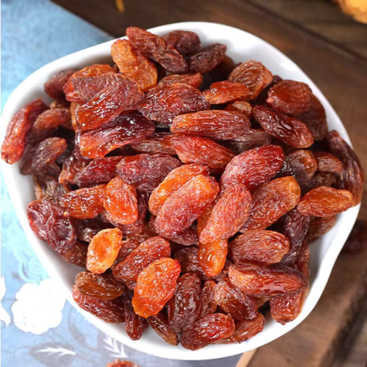 White bowl filled with dried raisins on a wooden surface