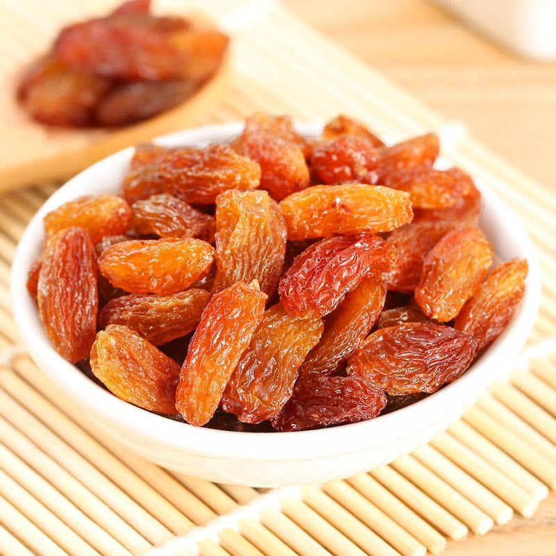 White bowl filled with dried raisins on a wooden surface