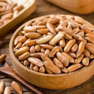 Wooden bowl filled with pine nuts on a wooden surface